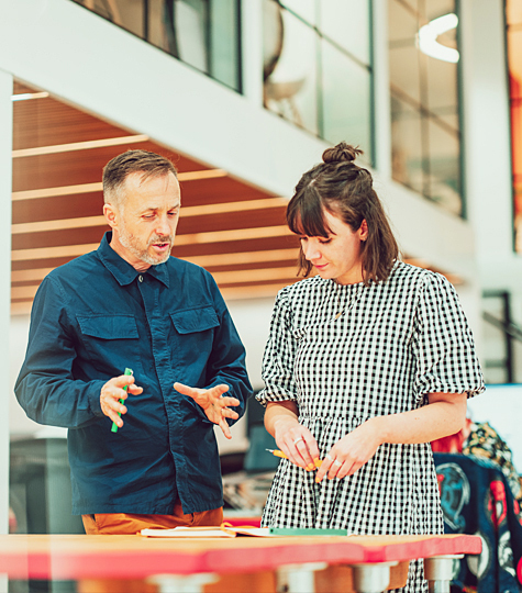 A brand consultant and a designer chatting about a client visual identity project, in the Birmingham agency's studio space