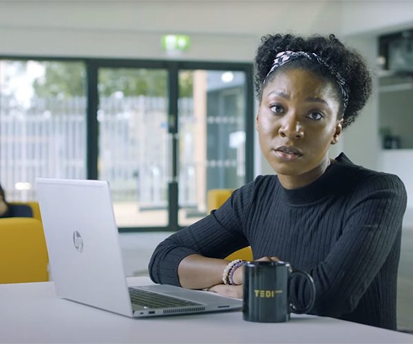 Student Grace shown talking in one of the Future Engineers campaign films. She's sitting at her laptop with a TEDI-London mug beside her. 