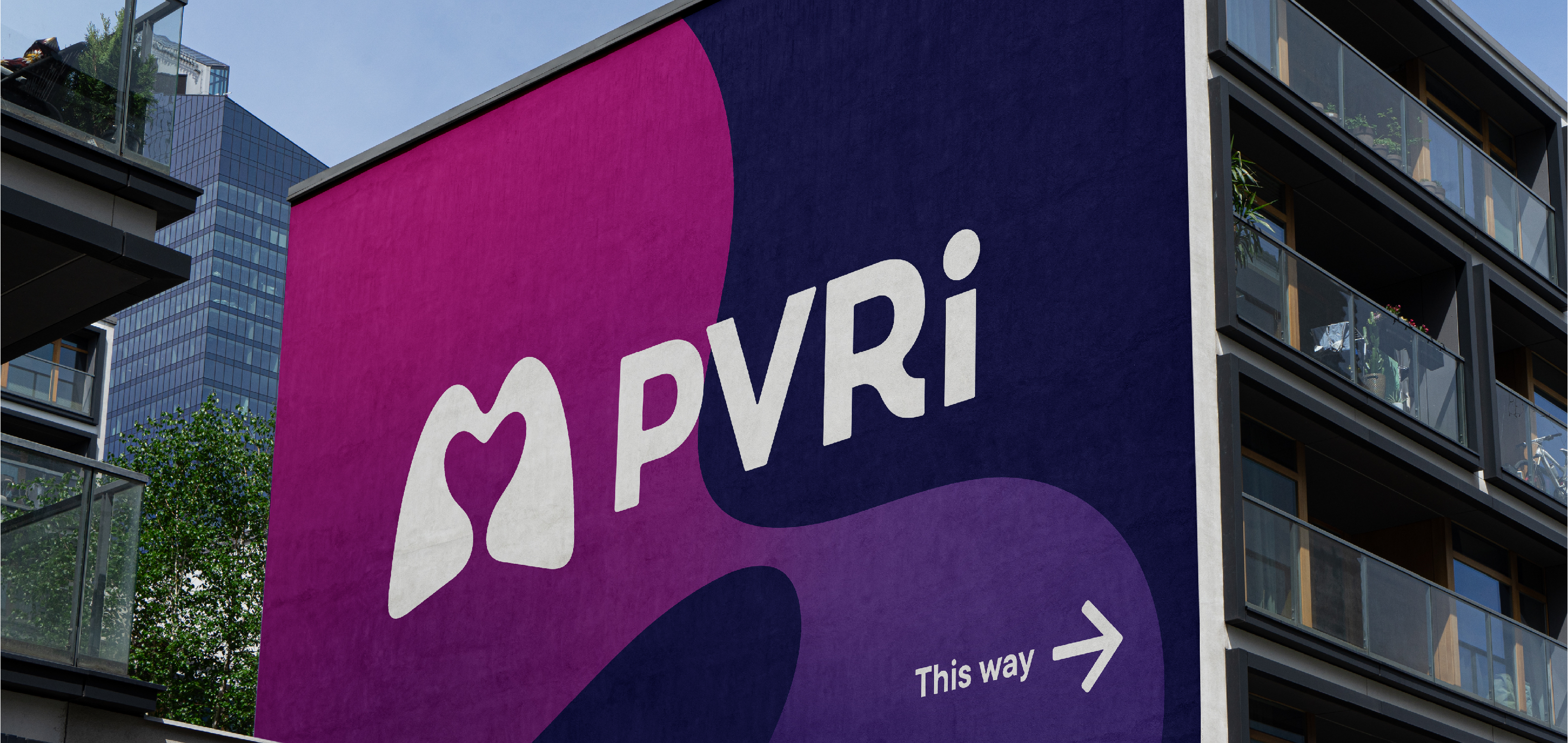 PVRI logo on the side of a building as signage for an event. Logo in white on a background of indigo, plum, pink and purple. 
