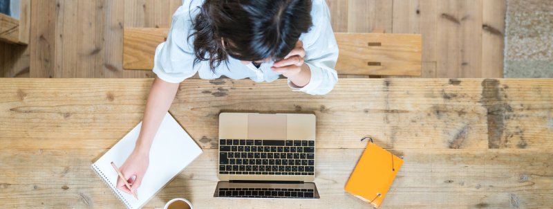 Aerial view of a young woman studying with laptop and notes