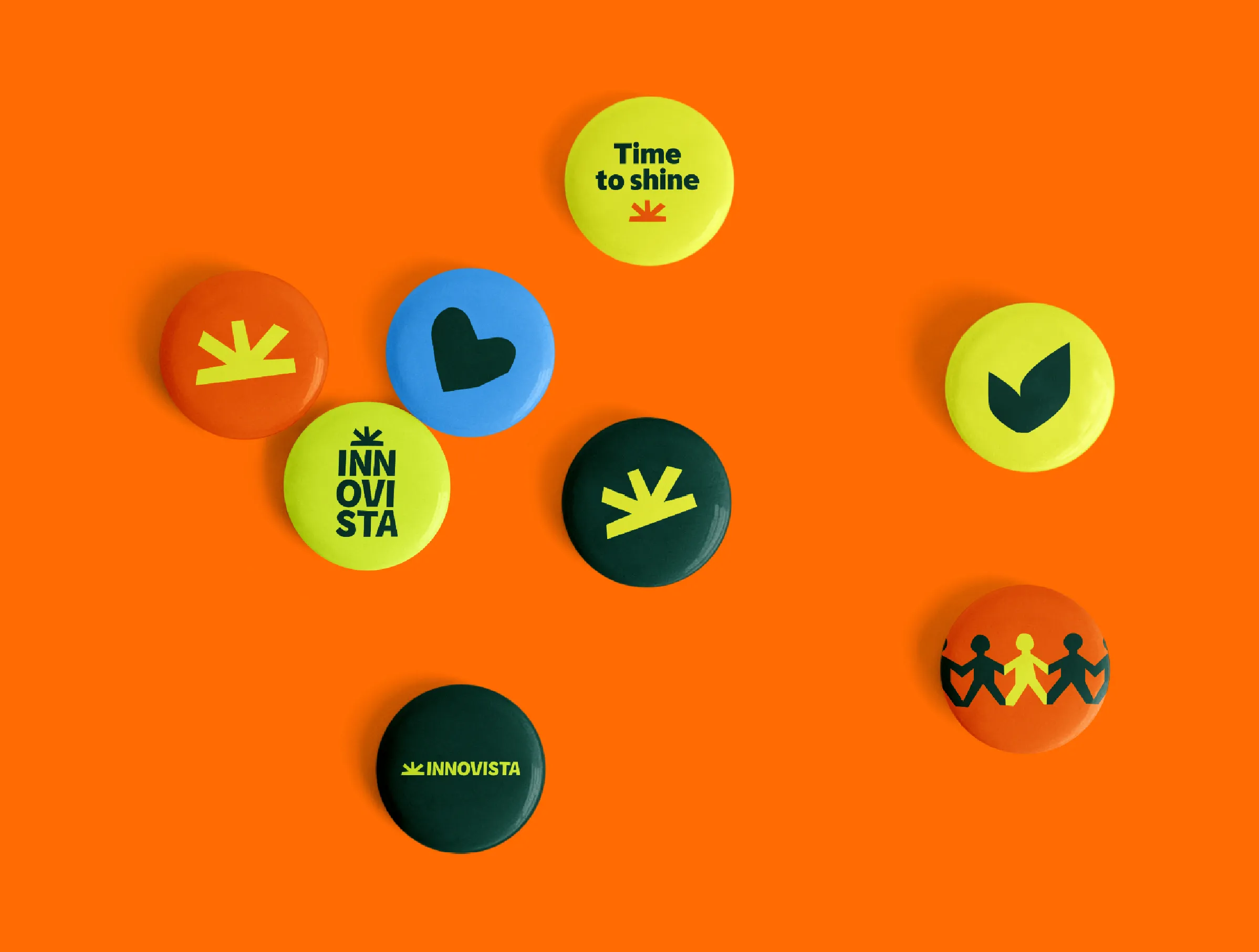 A set of small round badges on a bright orange background. The badges feature the Innovista sunrise icon, other cut-out style shapes, and the charity's logo